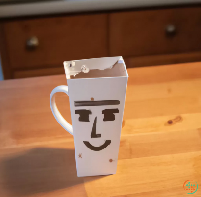 A white coffee mug with a face drawn on it