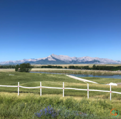 A white fence in front of a lake and mountains