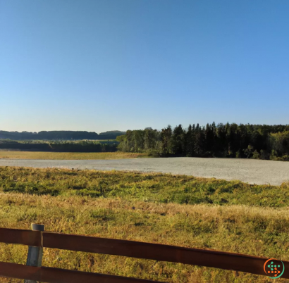 A field with a fence and trees in the background