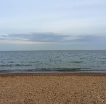 A beach with waves and a cloudy sky