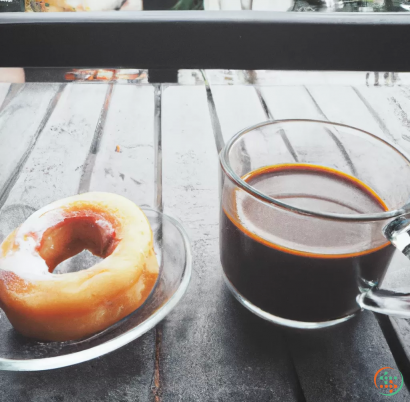 A cup of coffee next to a donut and a glass of coffee