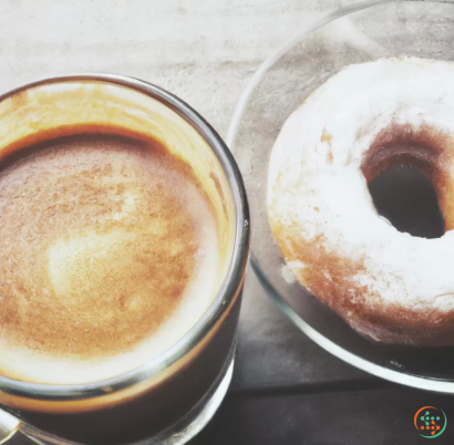 A cup of coffee next to a donut and a donut