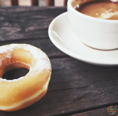 A donut next to a cup of coffee