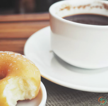 A cup of coffee next to a plate of donuts