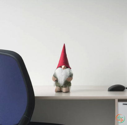 A small white animal wearing a red hat and sitting on a desk