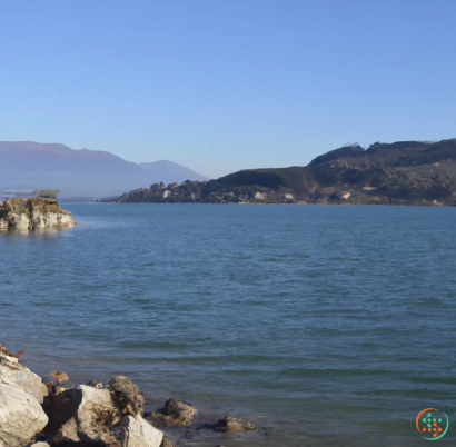 A body of water with rocks and hills in the background