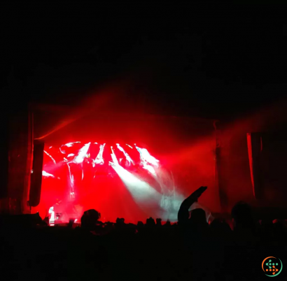 A crowd of people in front of a stage with a bright light