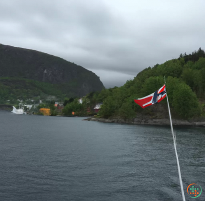 A flag on a pole in the water with mountains in the background